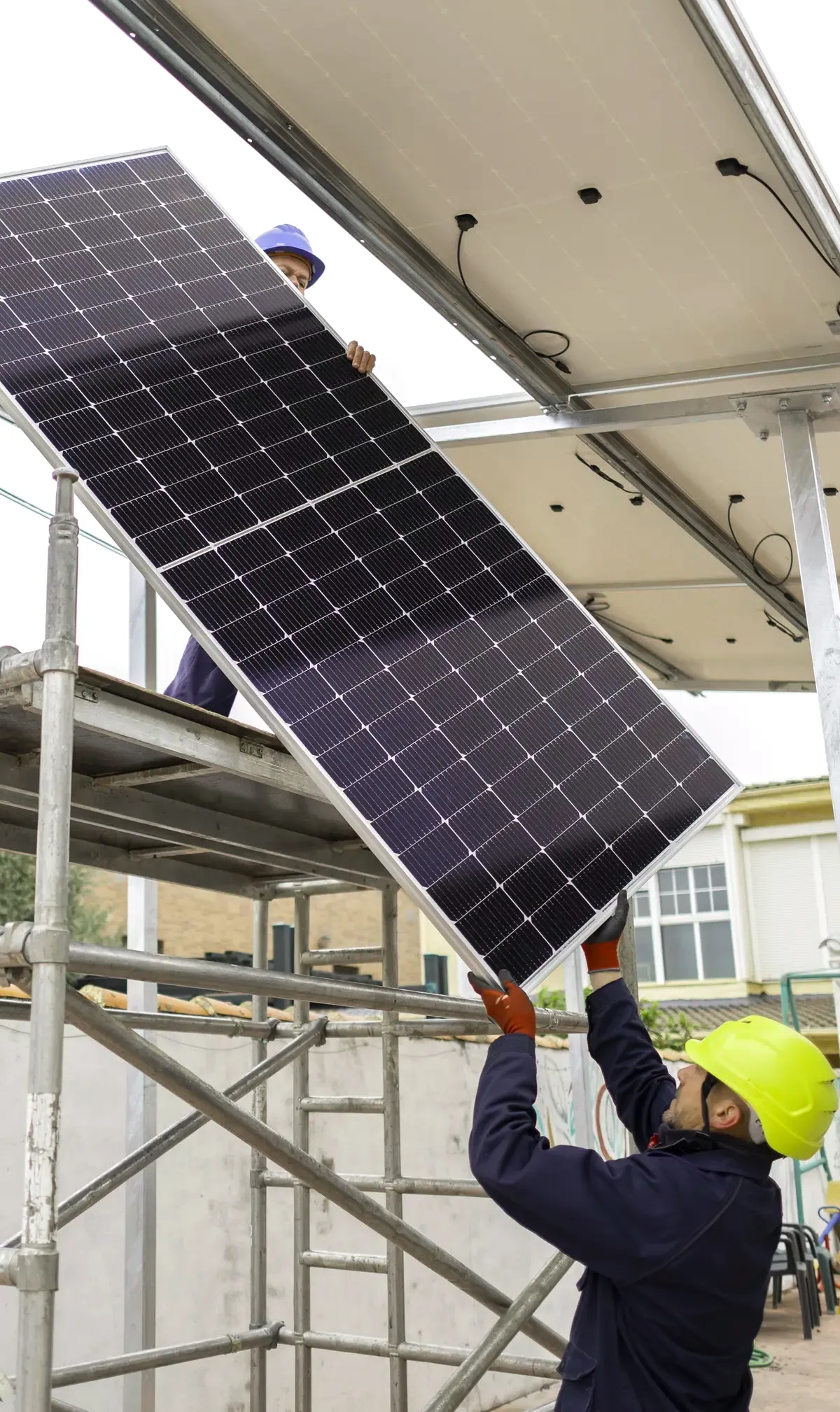 Dos operarios montan paneles solares con andamio en una finca de Barcelona